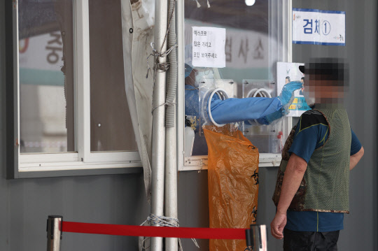 지난 25일 오전 서울역 광장에 마련된 중구임시선별검사소에서 의료진이 검체를 채취하고 있다. 연합뉴스.